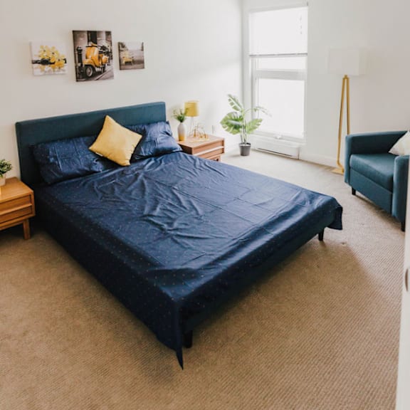 a bedroom with a bed, a chair, and pictures on the wall.