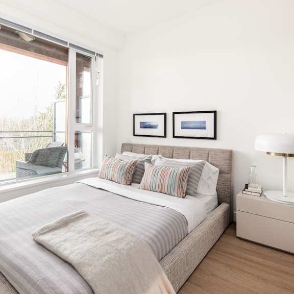 a bedroom with a large bed and a window overlooking a balcony.