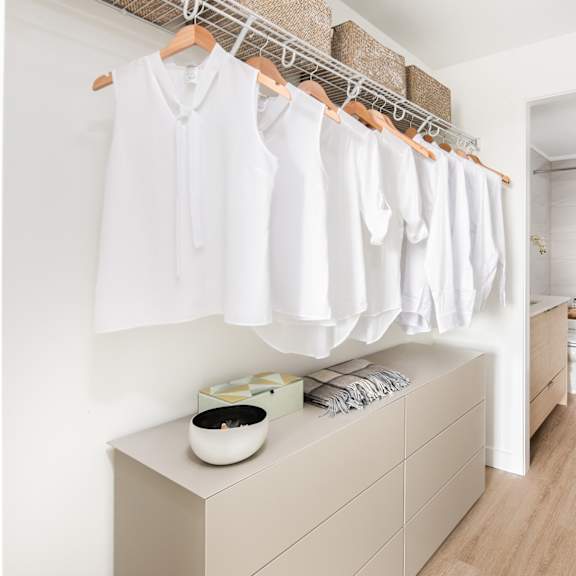 a row of white shirts hanging on a rack in a room.