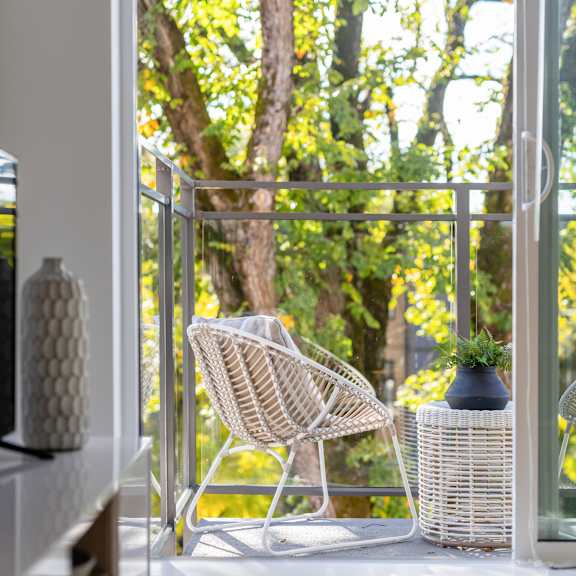 a white chair is on a balcony with a view of trees.