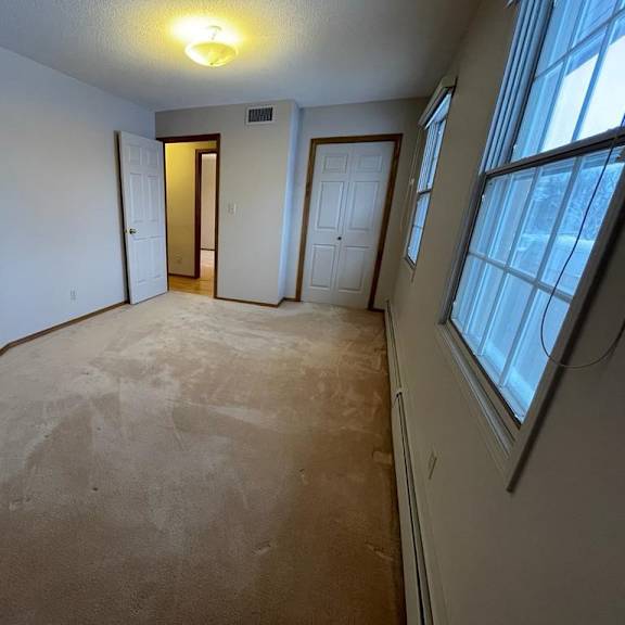 a room with a carpeted floor and a window on the right side.