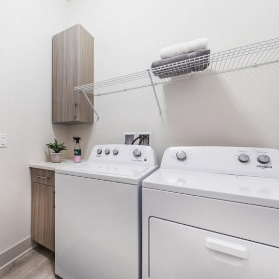 a utility room with a washer and dryer and a kitchen in the background