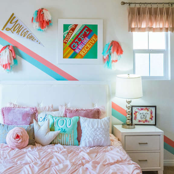 Thumbnail 4 of 4 a bedroom with a bed with pink pillows and a rainbow wall