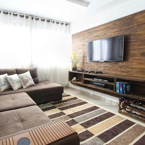 a living room with a large brown couch and a flat screen tv on the wall