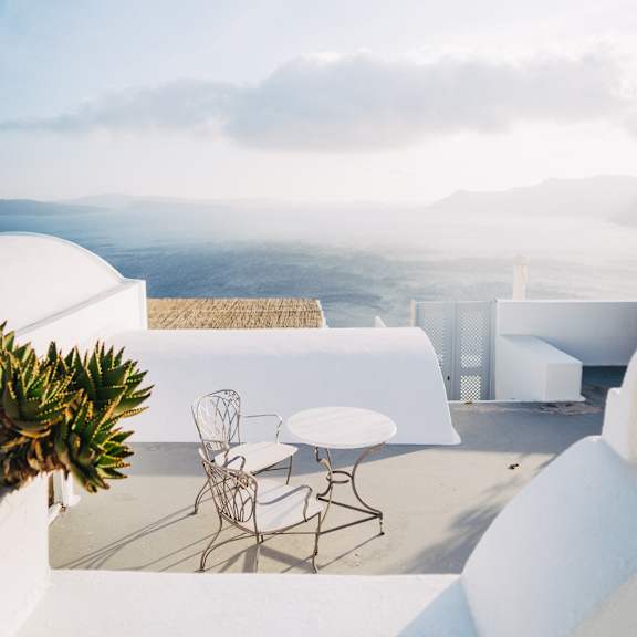 a table and chairs are on a patio overlooking a mountainous landscape.