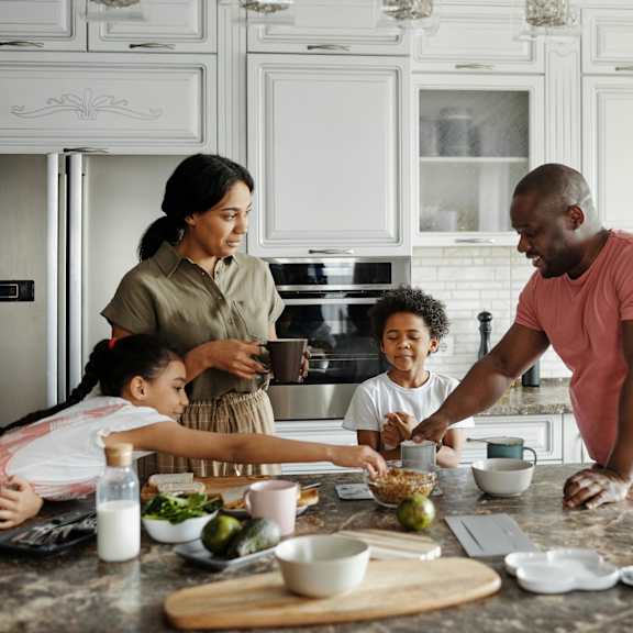 a family of four is preparing a meal together in a kitchen.