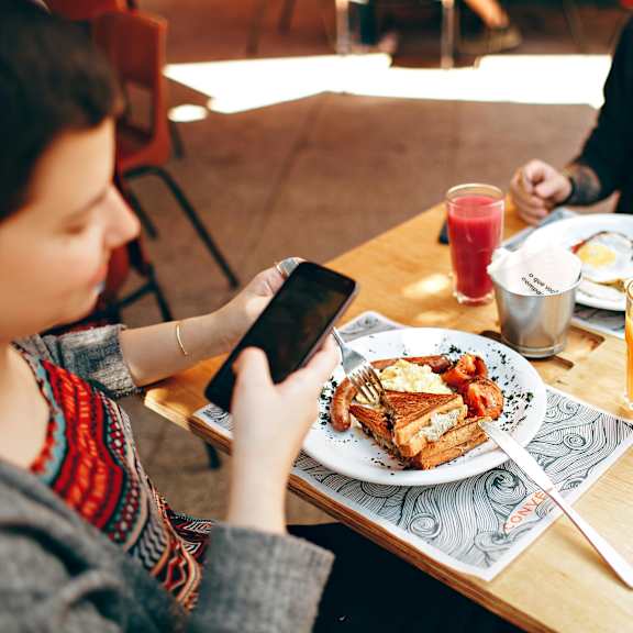 a person is sitting at a table with a plate of food and a glass of juice.
