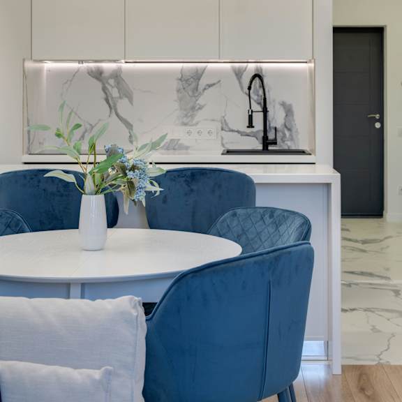 a dining area with a white table and blue chairs.