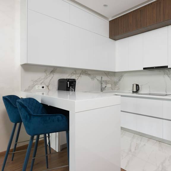 a kitchen with white cabinets and a marble backsplash.