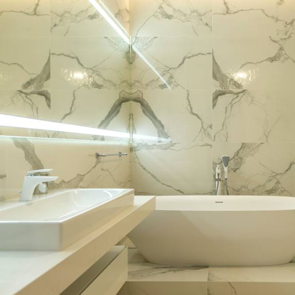 a bathroom with a marble wall and a white bathtub.