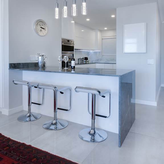 a kitchen with a long counter and three stools in front of it