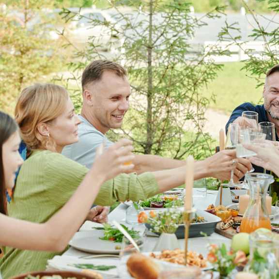 a group of people toasting with drinks at a dinner table.