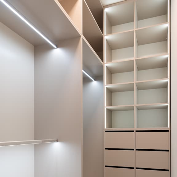 a walk in closet with white shelving and a wood floor