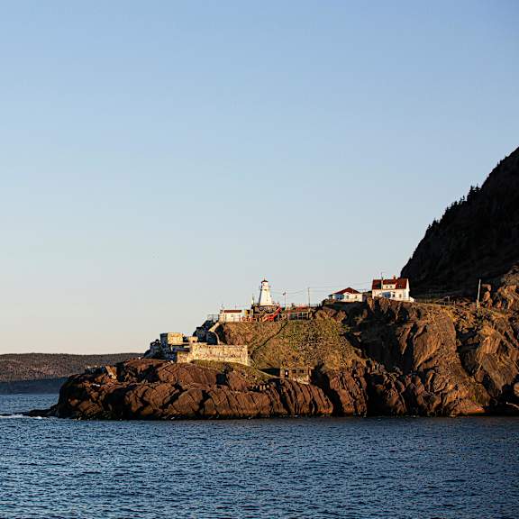a lighthouse sits on a rocky outcrop surrounded by water.