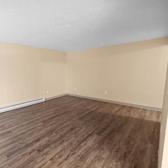 a room with wooden flooring and beige walls.