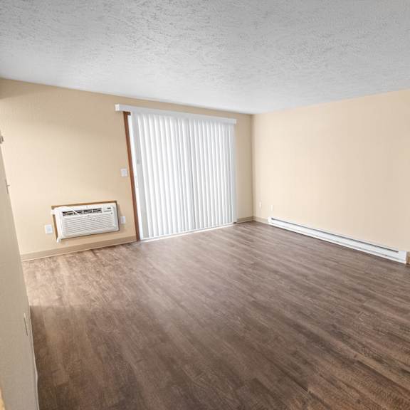 a room with wooden flooring and a window with blinds.
