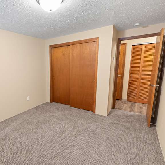 a room with a carpeted floor and two wooden doors.
