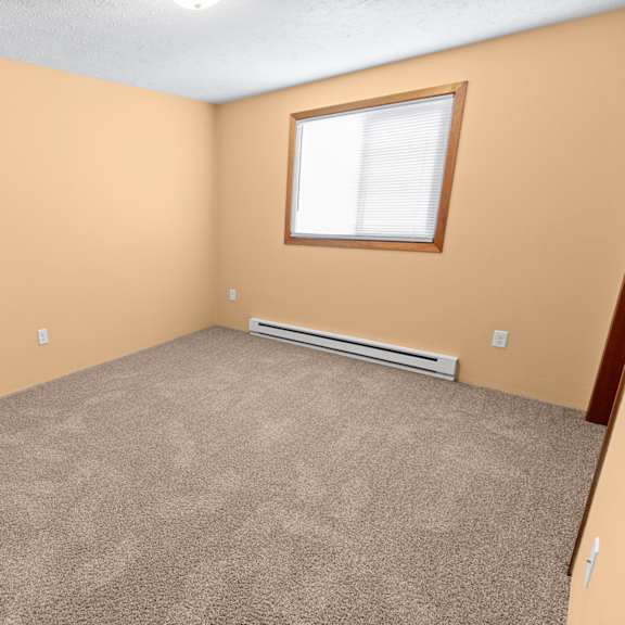 a room with a window and a carpeted floor.