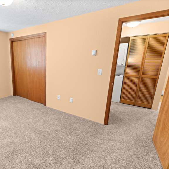 a room with a carpeted floor, a window, and a wooden door.