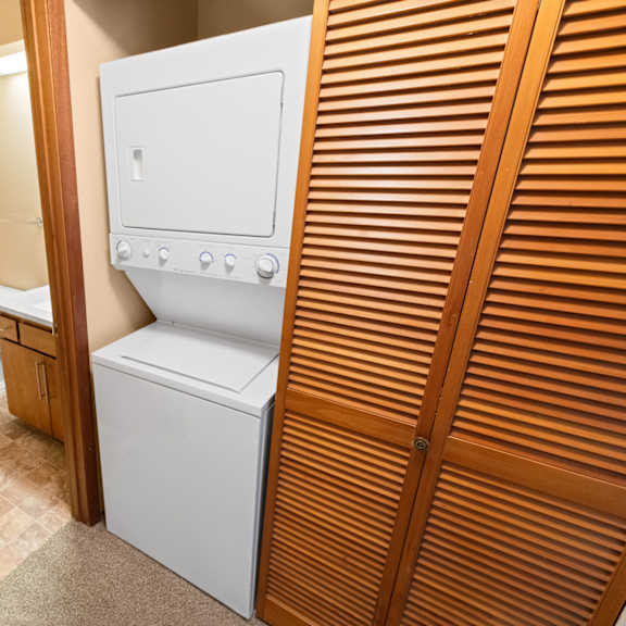 a white dryer is in a small room with a toilet in the background.