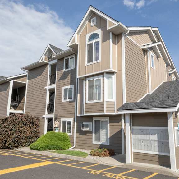 a large, multi-story residential building with a parking lot in front.