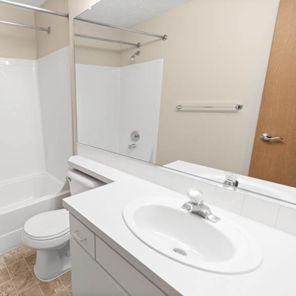 a white bathroom with a toilet, sink, and bathtub.
