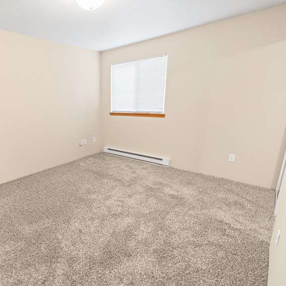 a room with a carpeted floor and a window with blinds.