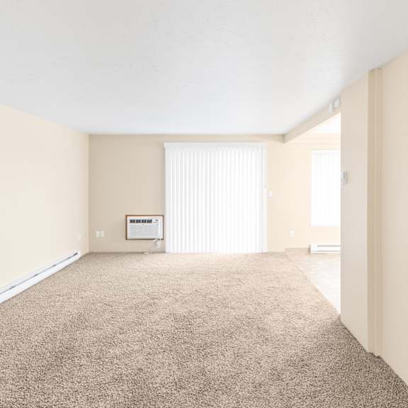 a large, empty room with a carpeted floor and a window with blinds.