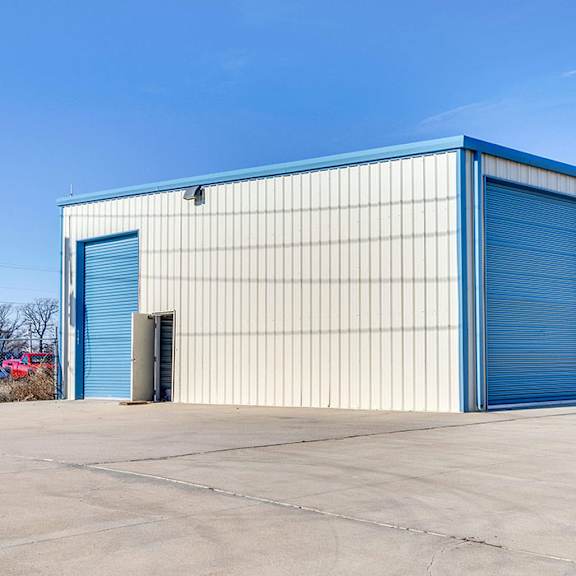 a large industrial building with blue doors and a white facade.