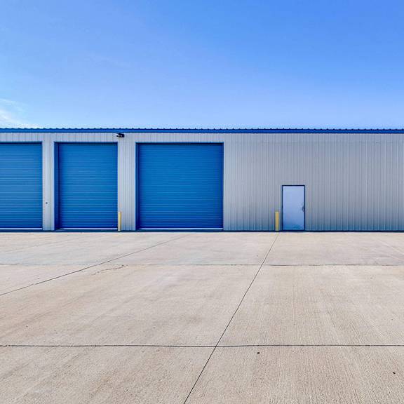 a large industrial building with blue doors and a grey roof.