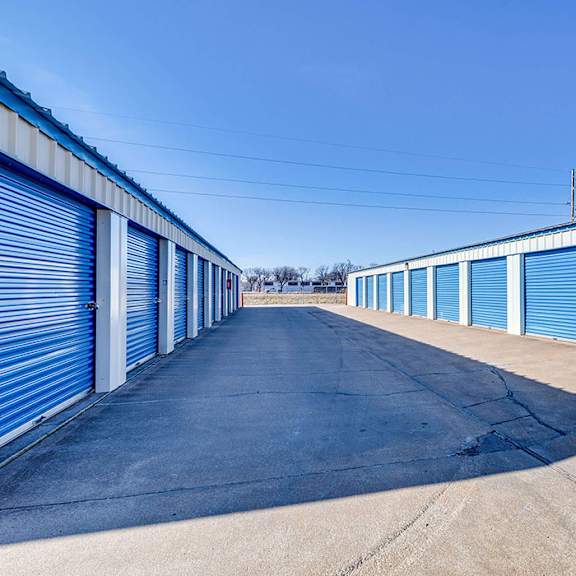 a long row of blue storage units with a clear blue sky above.