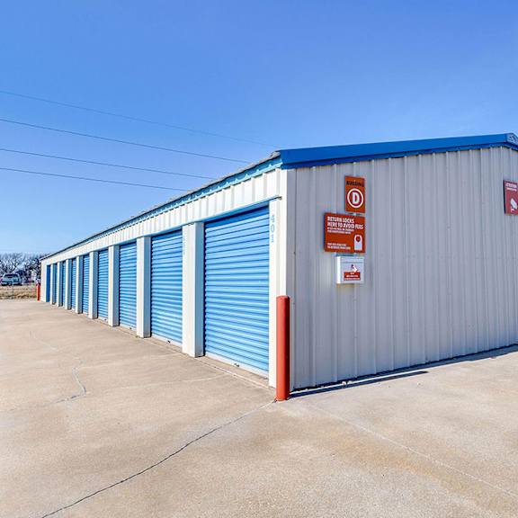 a storage facility with blue doors and a red and white sign.