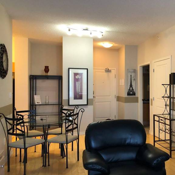 a black leather sofa sits in a living room with a glass table and chairs.