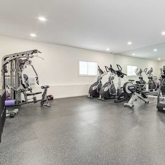 a spacious gym with treadmills, exercise bikes, and other equipment.