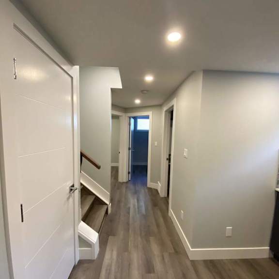a long hallway with white walls and wood flooring.