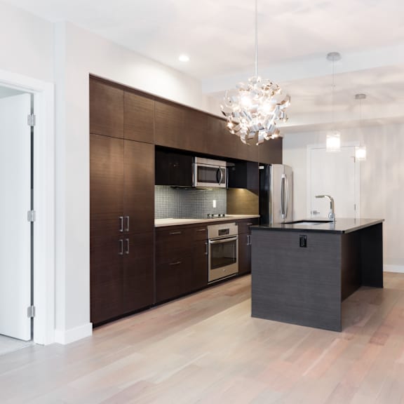 a modern kitchen with dark brown cabinets and a black island.