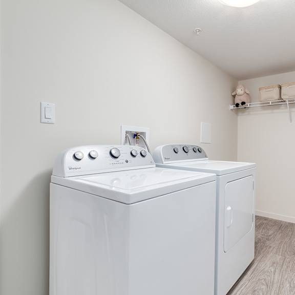 a laundry room with two washing machines and a clothes rack.