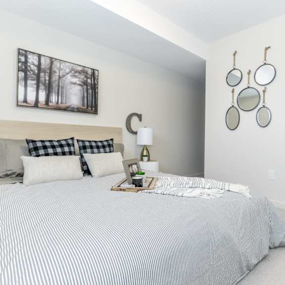 a bedroom with a bed, pillows, a nightstand, and a picture on the wall.