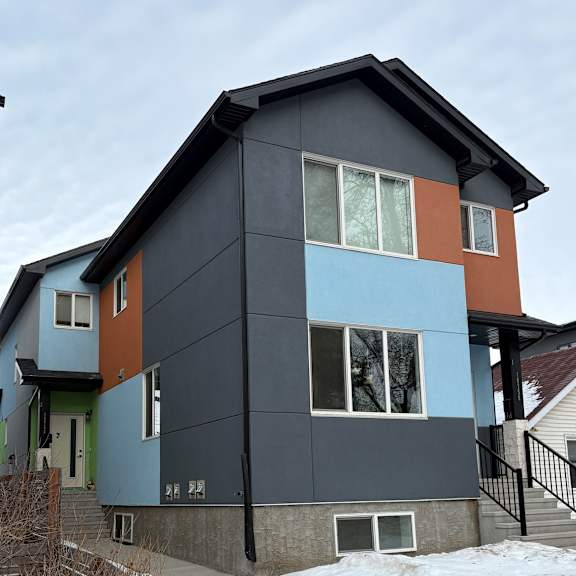a modern house with a black roof and a mix of blue and orange panels.