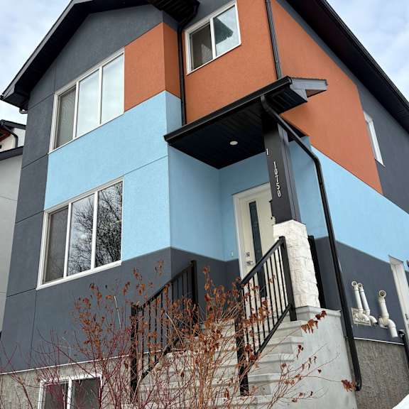 a modern house with a black balcony and a staircase.
