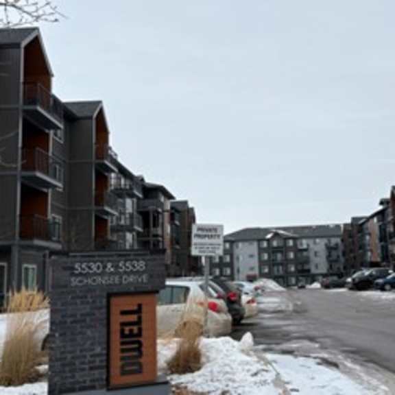 a street view of a dwell apartment complex with snow on the ground.