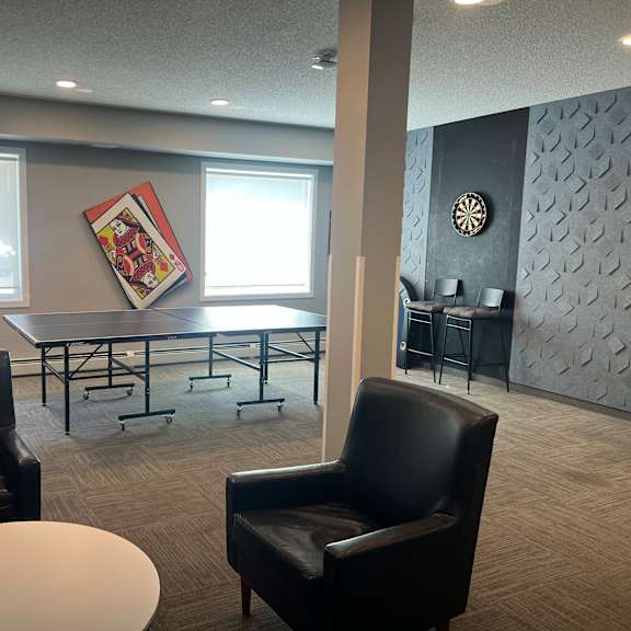 a conference room with two chairs, a table, and a wall clock.