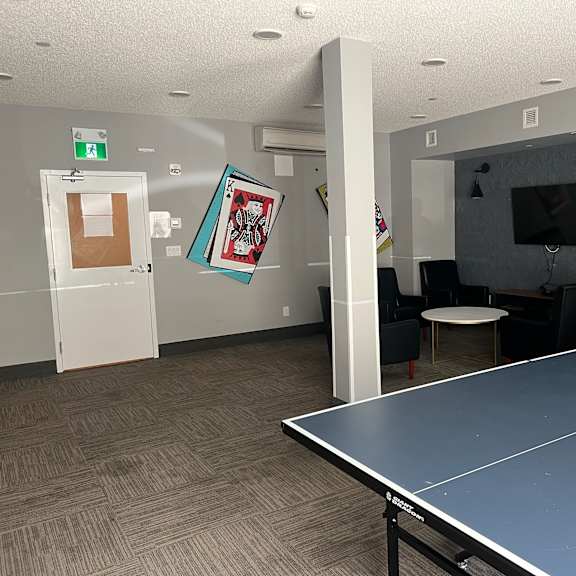 a woman stands in a room with a ping pong table.