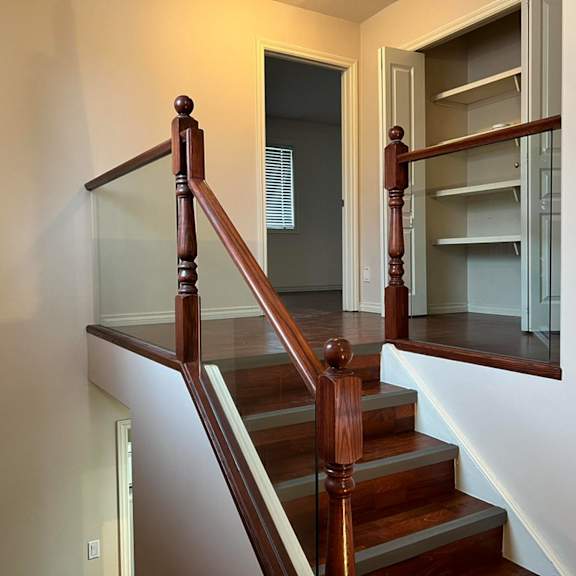 a staircase with a wooden handrail and glass balusters.