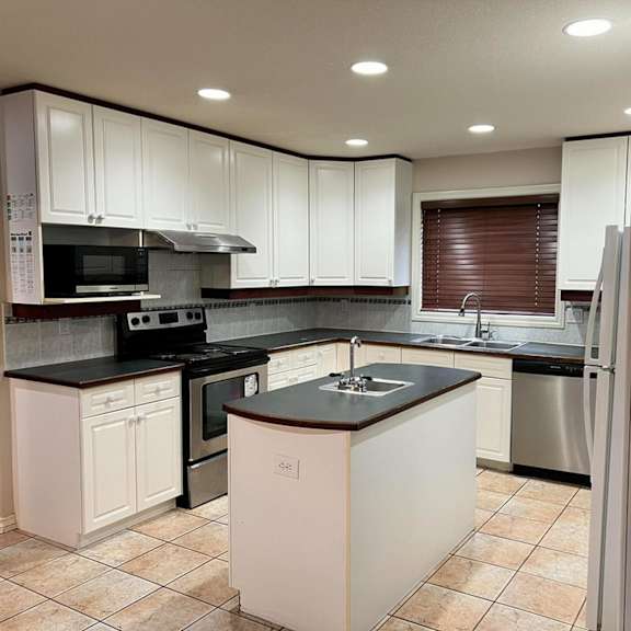 a kitchen with white cabinets and a black countertop.