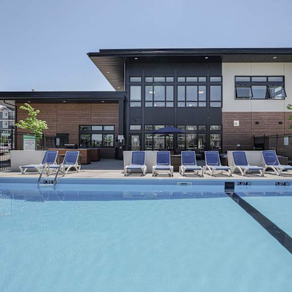 a swimming pool in front of a building with lounge chairs around it.