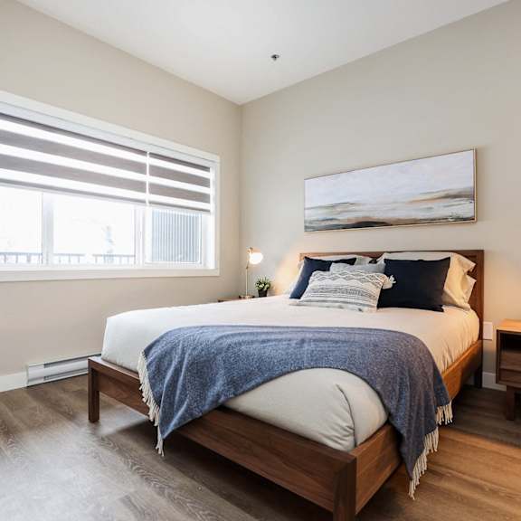 a bedroom with a bed, nightstand, and window with blinds.