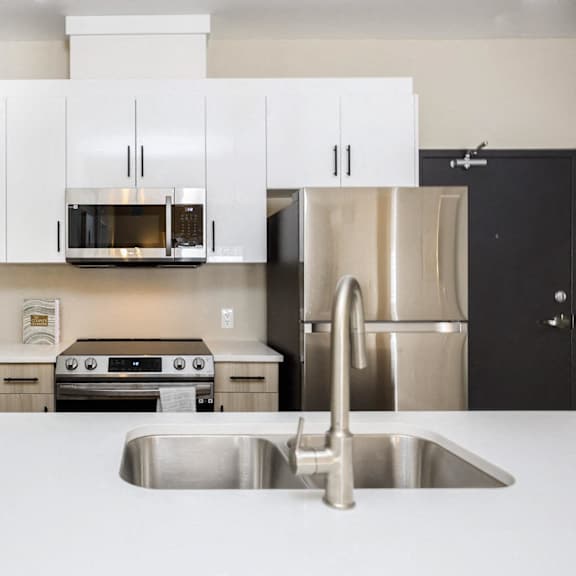 a modern kitchen with stainless steel appliances and white cabinets.