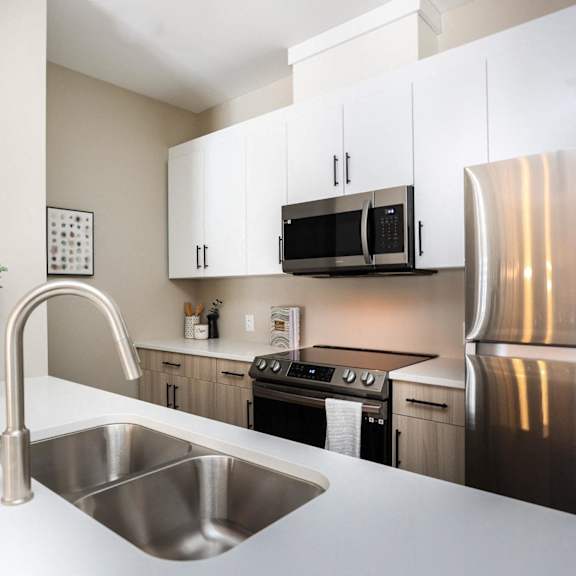 a modern kitchen with a stainless steel refrigerator and a sink with a faucet.
