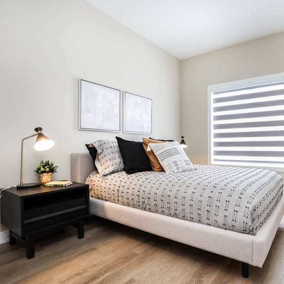 a bedroom with a bed, nightstand, and a lamp.